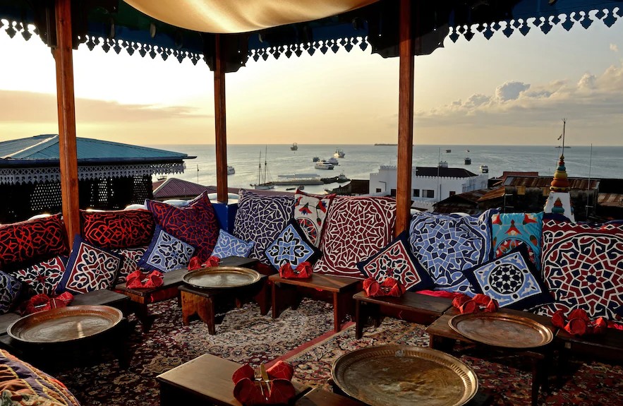 A rooftop terrace with cushions and lanterns above the harbour in Stone Town, Zanzibar